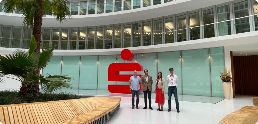 CEO von docu tools, Projektleiter und Team der Hamburger Sparkasse vor dem Sparkassen-Logo im Atrium des Deutschlandhauses